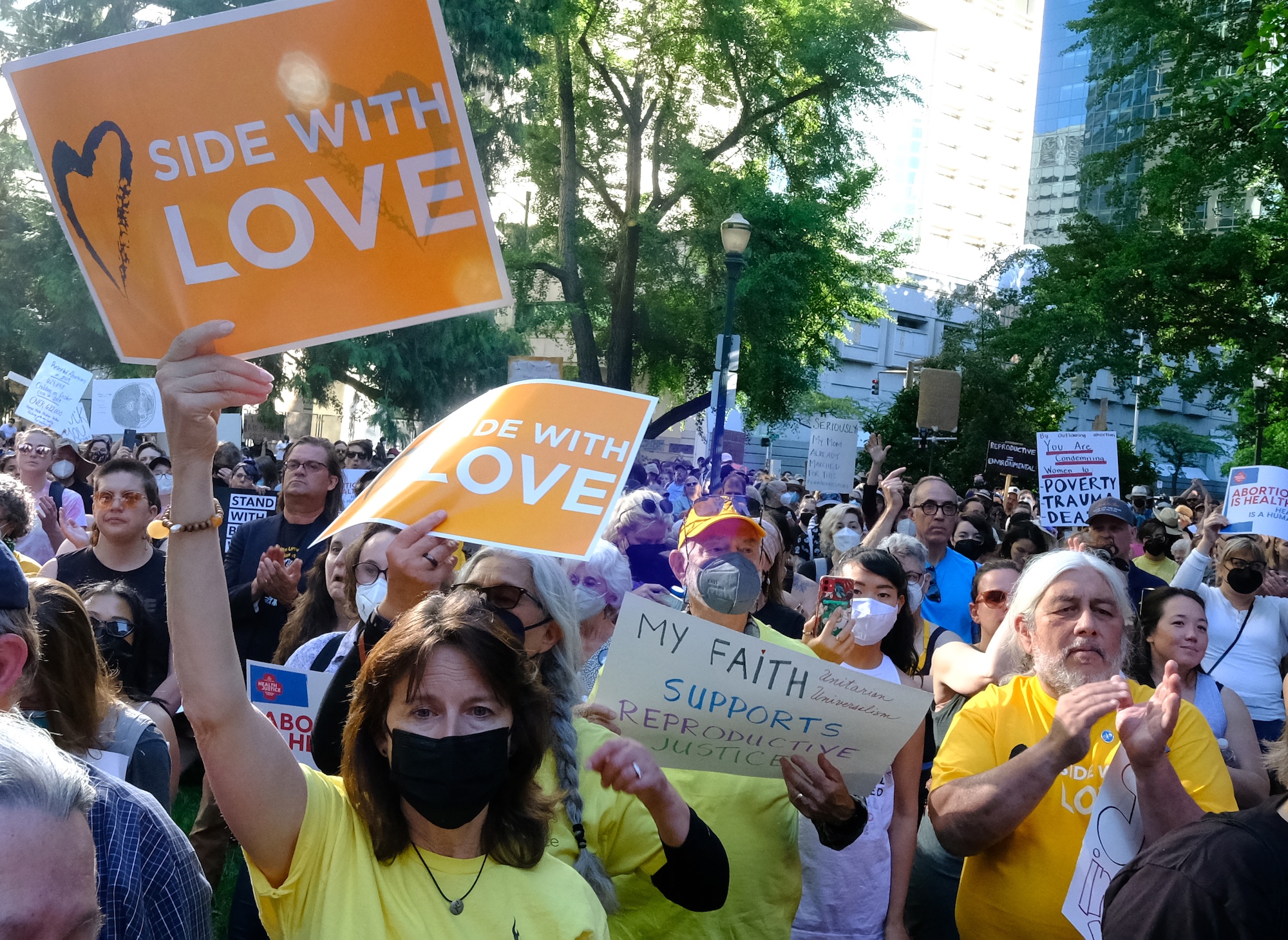 A large group of protestors—some in yellow "Side With Love" shirts, many holding sign—protest the U.S. Supreme Court ruling that overturned Roe v. Wade.